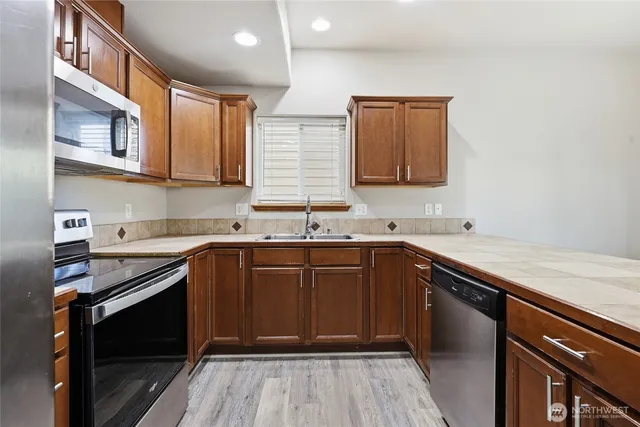 a kitchen with stainless steel appliances granite countertop a sink stove and cabinets