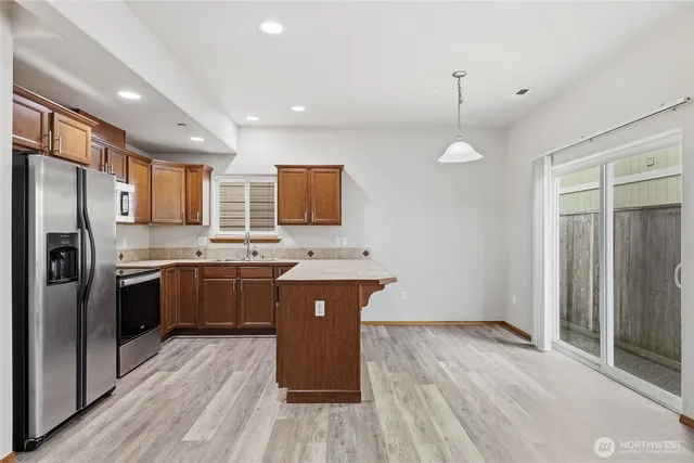 a kitchen with stainless steel appliances granite countertop a refrigerator a sink dishwasher a stove and white countertops with wooden floor