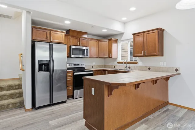 a kitchen with stainless steel appliances granite countertop a refrigerator a sink and a stove