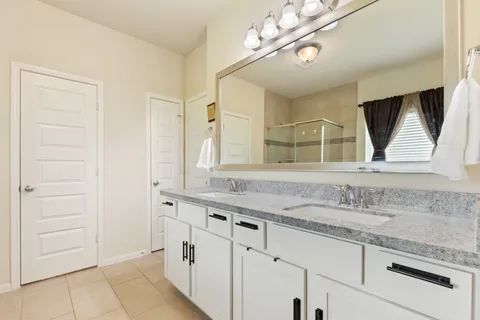 a bathroom with a granite countertop sink a mirror a bathtub and shower