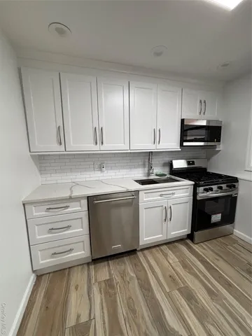a kitchen with granite countertop white cabinets and stainless steel appliances