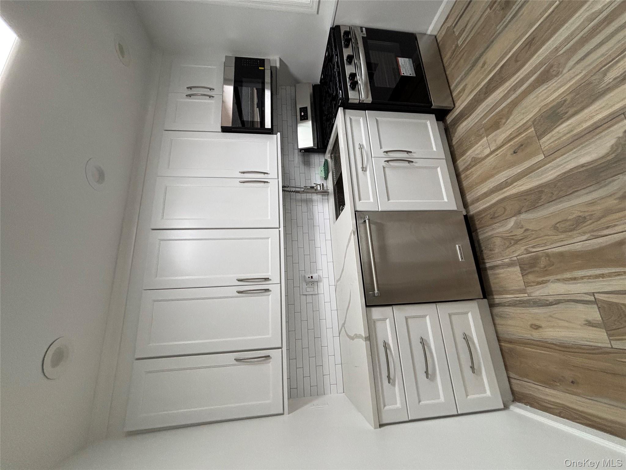 a kitchen with granite countertop white cabinets and stainless steel appliances