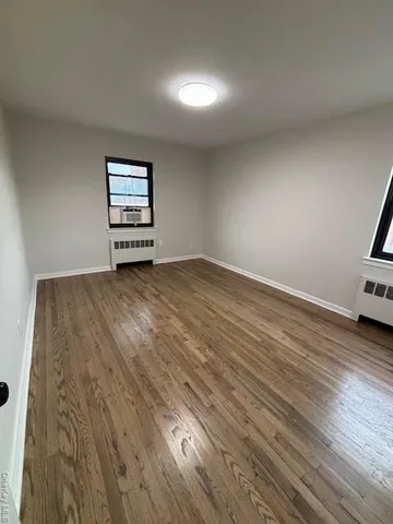 an empty room with wooden floor closet and windows
