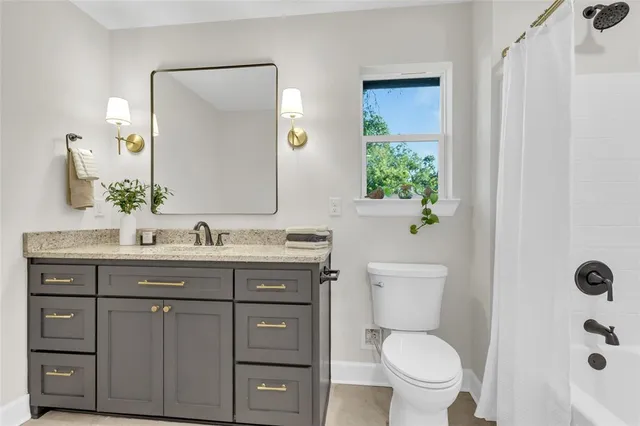 a bathroom with a granite countertop toilet a sink and a mirror