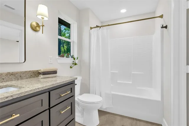 a bathroom with a granite countertop sink a toilet and shower