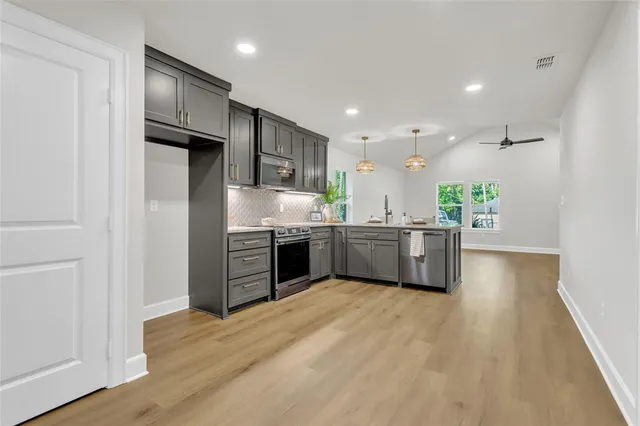 a kitchen with stainless steel appliances a sink cabinets and wooden floor