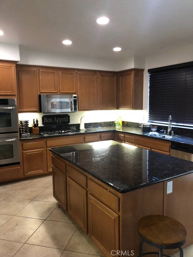 14653 Meadowsweet Drive Eastvale, CA 92880 - Photo 2 of 15 a kitchen with kitchen island granite countertop a sink a counter top space cabinets and stainless steel appliances