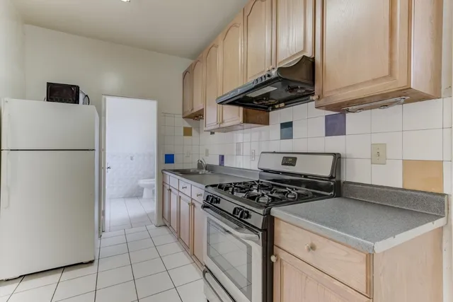 a kitchen with granite countertop a stove sink and refrigerator