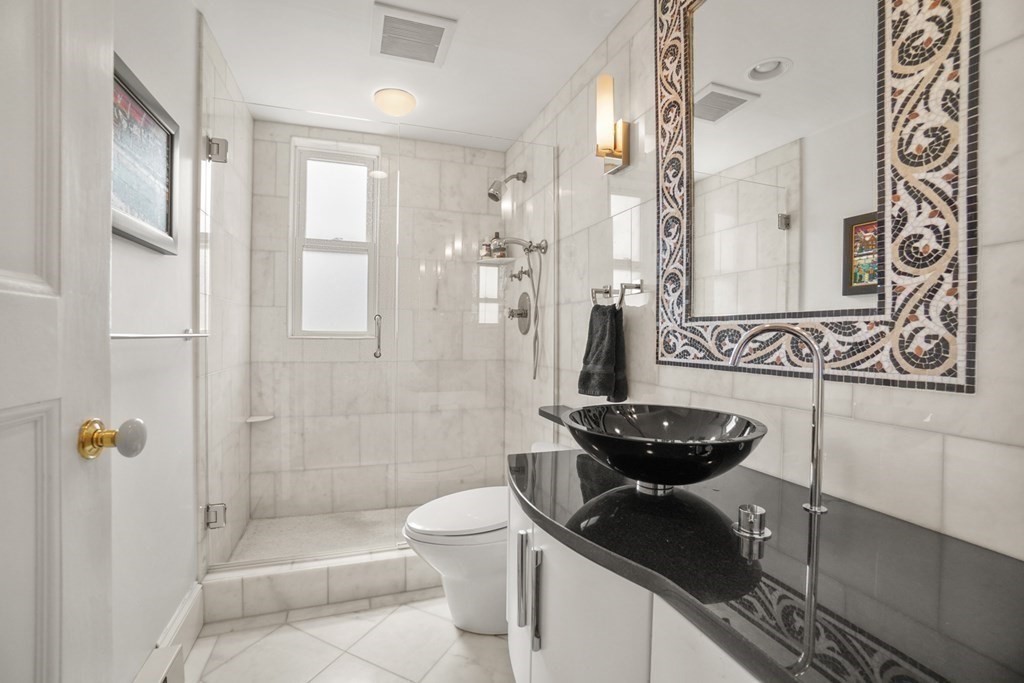 333 Commonwealth Avenue, Unit PH22 Boston, MA 02115 - Photo 25 of 42 a bathroom with a granite countertop sink a toilet a mirror and shower