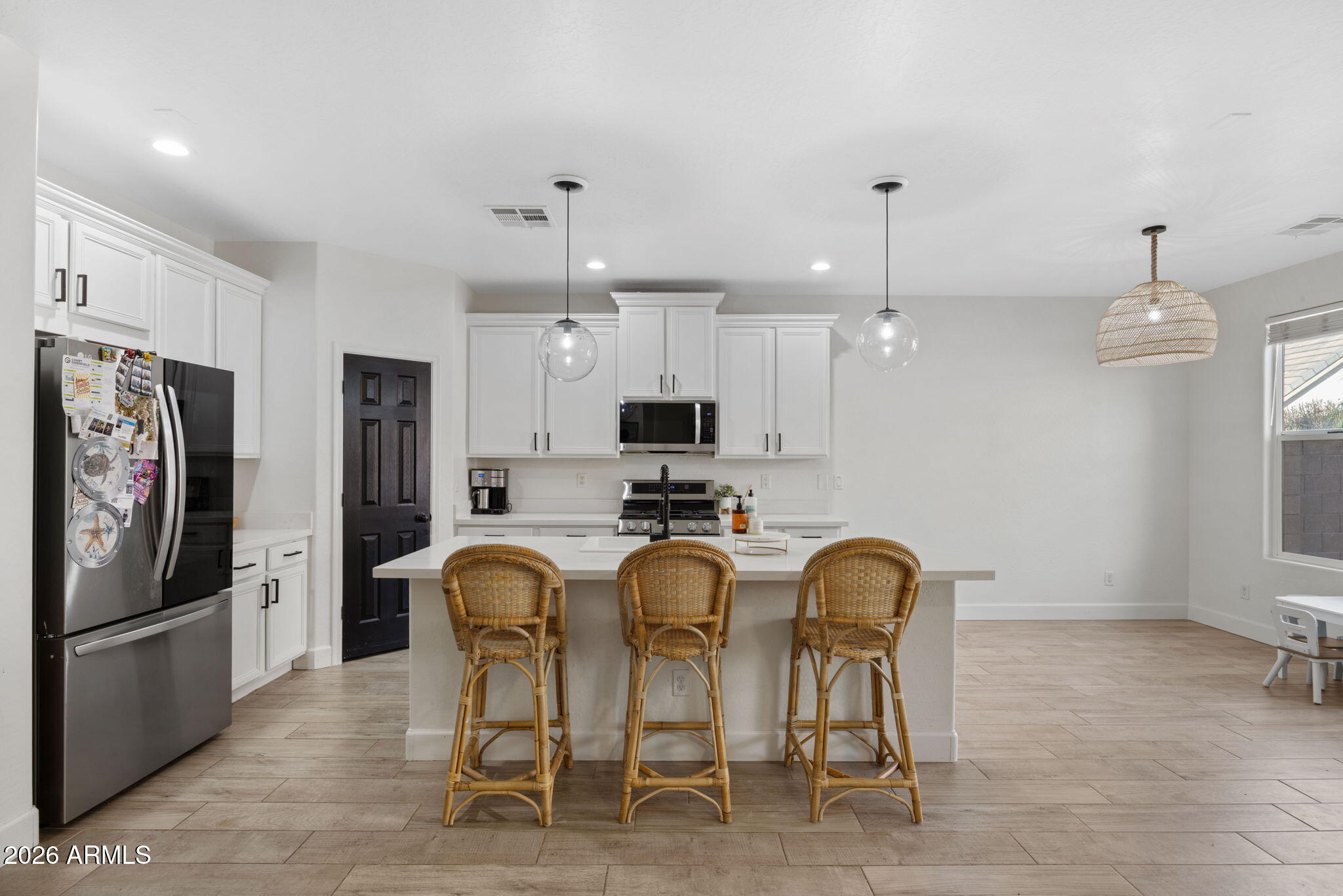 3458 East Robin Lane Gilbert, AZ 85296 - Photo 8 of 32 a kitchen with stainless steel appliances a refrigerator a sink dishwasher a dining table and chairs with wooden floor