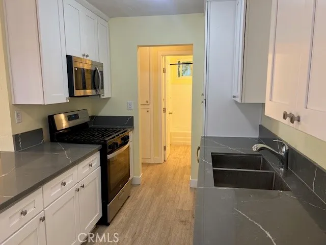 a kitchen with granite countertop a sink stove and cabinets