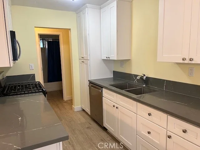 a kitchen with granite countertop a sink a stove and cabinets