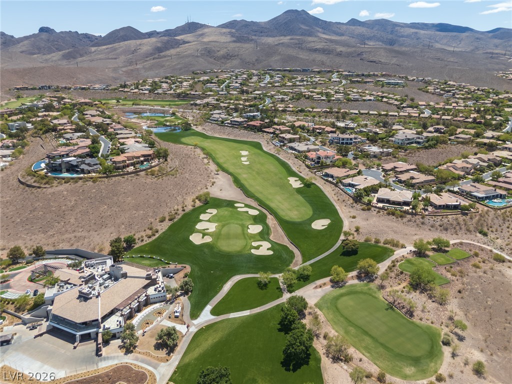 22 Douglas Grove Road Henderson, NV 89052 - Photo 4 of 72 An aerial perspective reveals a luxurious community set against a mountainous backdrop, featuring a golf course and elegant residences.