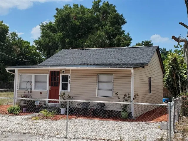 a view of a white house with a yard and large tree