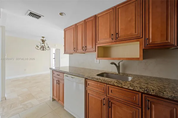 a kitchen with granite countertop a sink a stove and cabinets