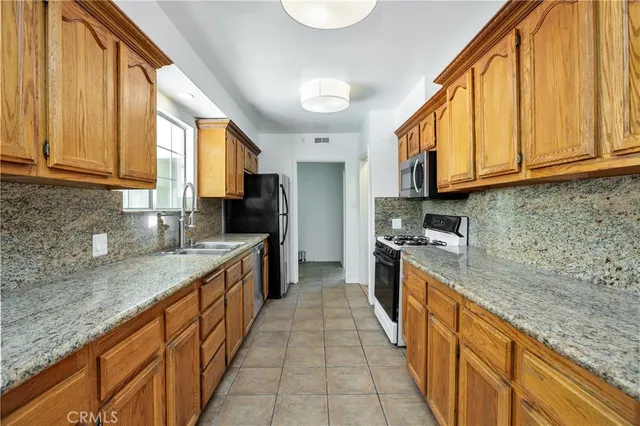 a large kitchen with stainless steel appliances granite countertop a sink and a counter space