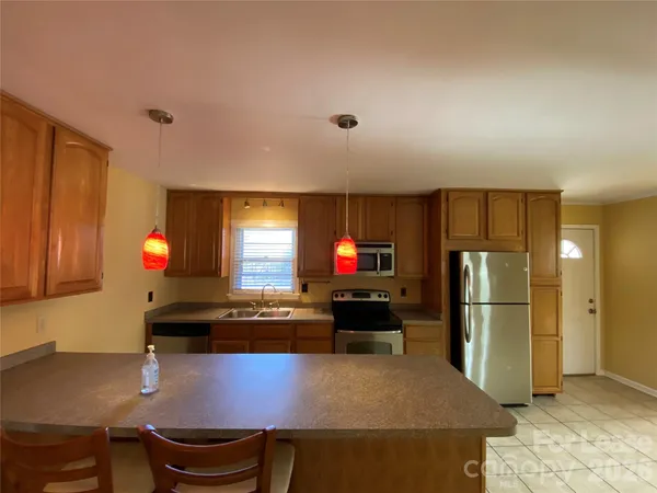 a kitchen with stainless steel appliances granite countertop a refrigerator a stove and a sink