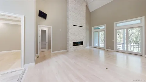 a view of an empty room with window and wooden floor