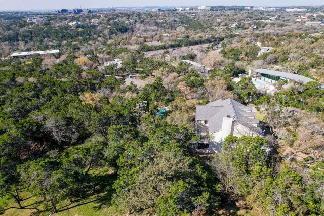 an aerial view of residential house with outdoor space and trees all around