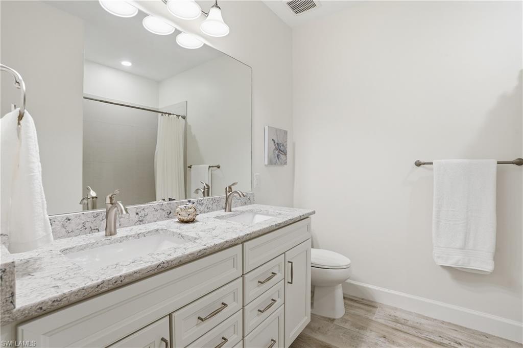 17210 Ashcomb Way Estero, FL 33928 - Photo 28 of 47 a bathroom with a granite countertop sink a toilet and a mirror