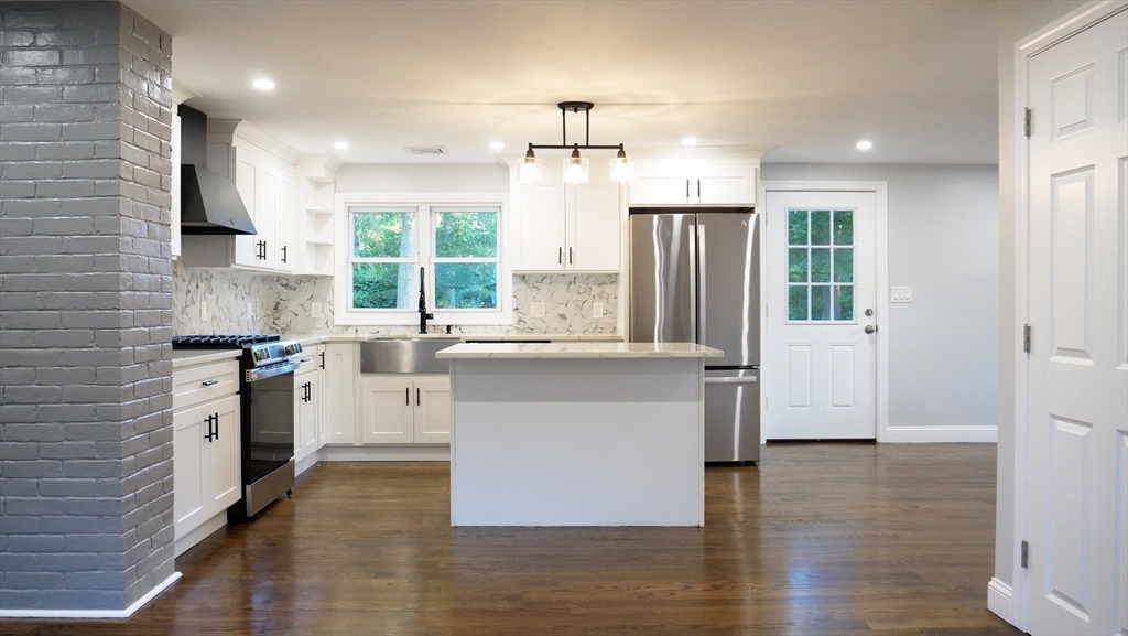 11 Christopher Road Brockton, MA 02302 - Photo 4 of 22 a kitchen with kitchen island granite countertop a stove a sink a refrigerator and white cabinets with wooden floor