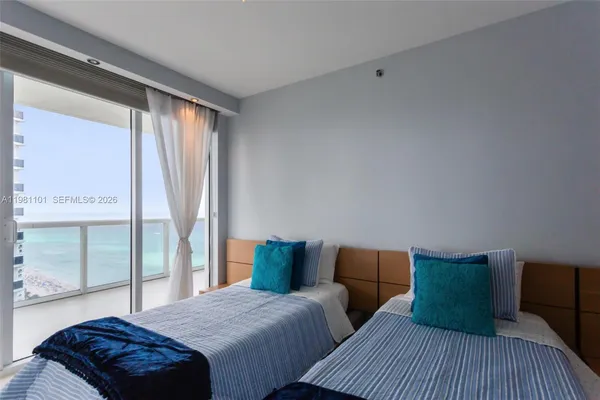 a bedroom with two beds and large window