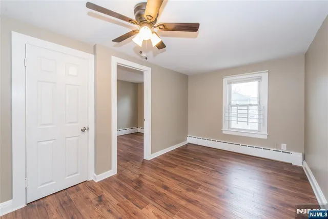 an empty room with wooden floor fan and windows