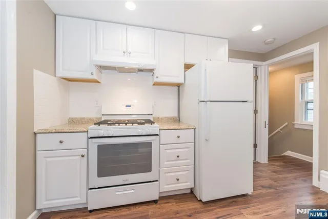 a kitchen with cabinets appliances and wooden floor