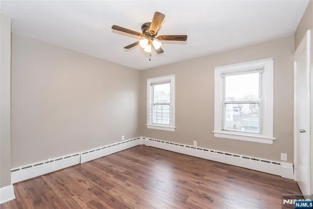 an empty room with wooden floor fan and windows