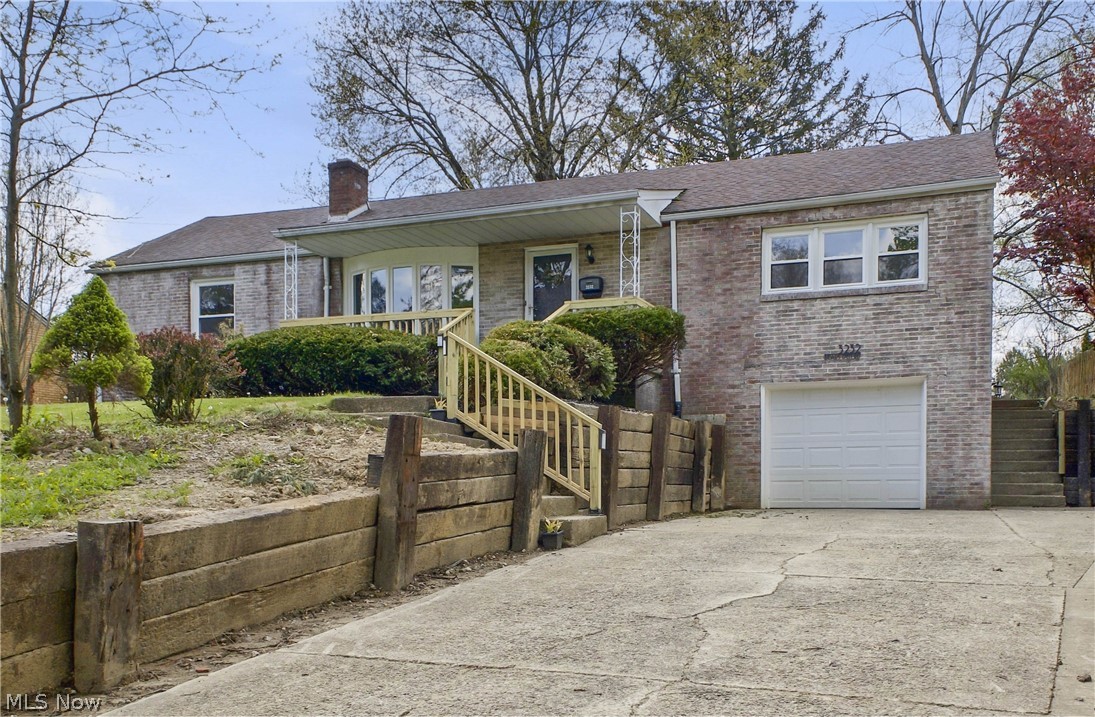 3232 Bears Den Road Youngstown, OH 44511 - Photo 1 of 38 Brick exterior with an attached garage, offering a driveway and wood retaining wall