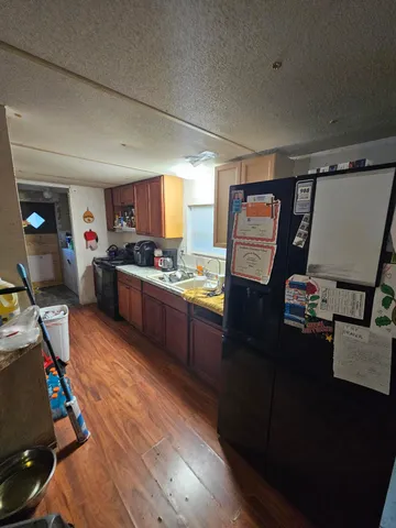 a kitchen with stainless steel appliances granite countertop a refrigerator a stove and a sink with wooden floors