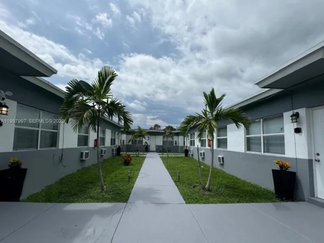 a front view of a house with a yard and potted plants
