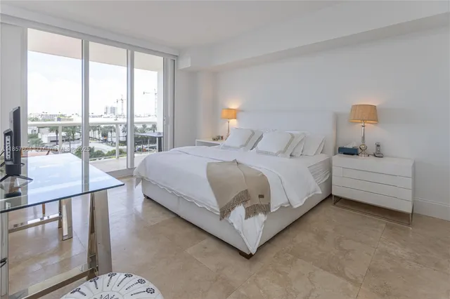 a bedroom with a bed lamp and a large window