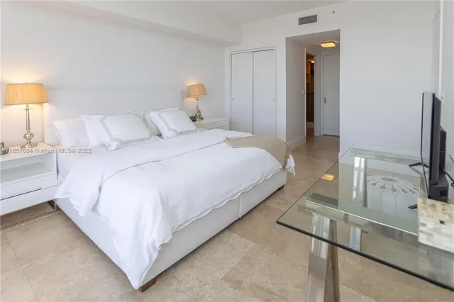 a bedroom with a bed and a flat tv screen on dresser