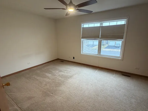 an empty room with windows and fan