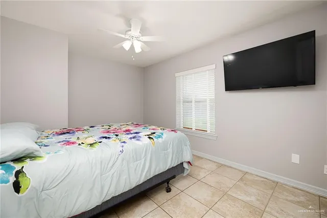 a bedroom with a bed a flat tv screen and a chandelier