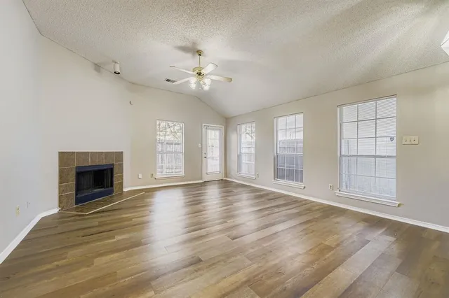an empty room with wooden floor chandelier and windows