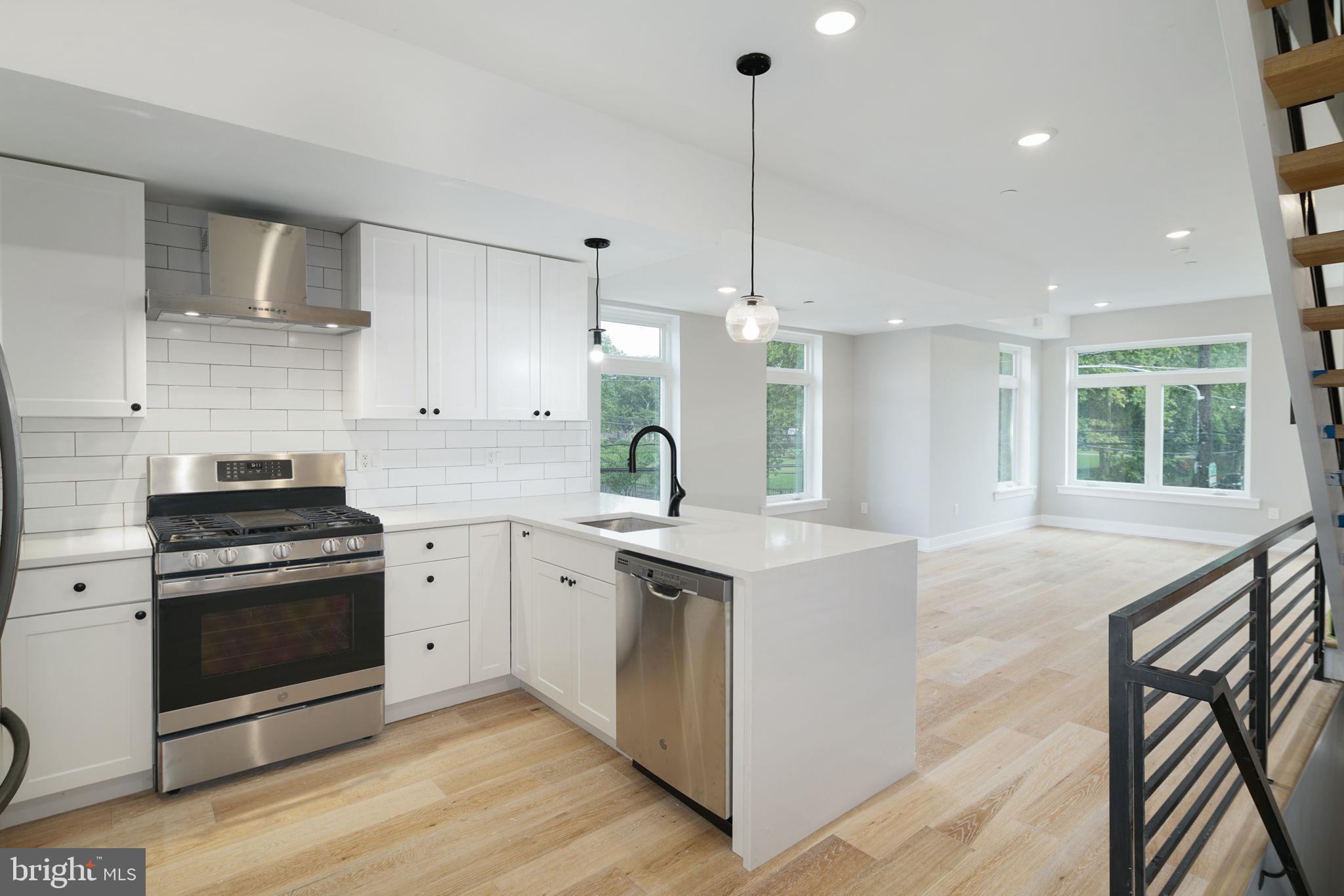 a kitchen with stainless steel appliances granite countertop a stove a sink a refrigerator and a wooden floor