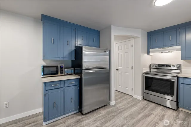 a kitchen with a refrigerator stove and wooden cabinets