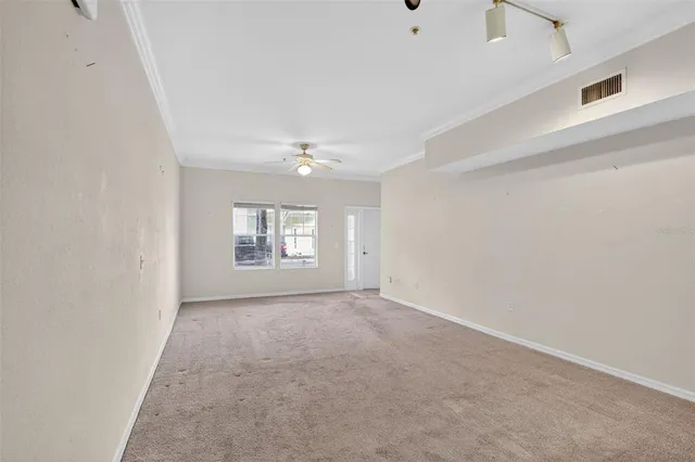 an empty room with windows and chandelier fan