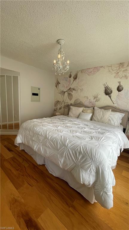 267 Quail Forest Boulevard, Unit 111 Naples, FL 34105 - Photo 17 of 41 a bedroom with a bed and wooden floor