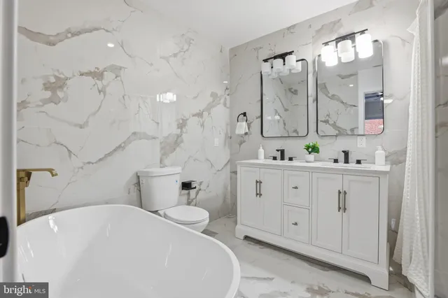 a spacious bathroom with a double vanity sink toilet mirror and bathtub