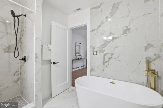 a bathroom with a white bath tub sitting next to shower