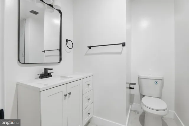 a bathroom with a toilet sink vanity and mirror