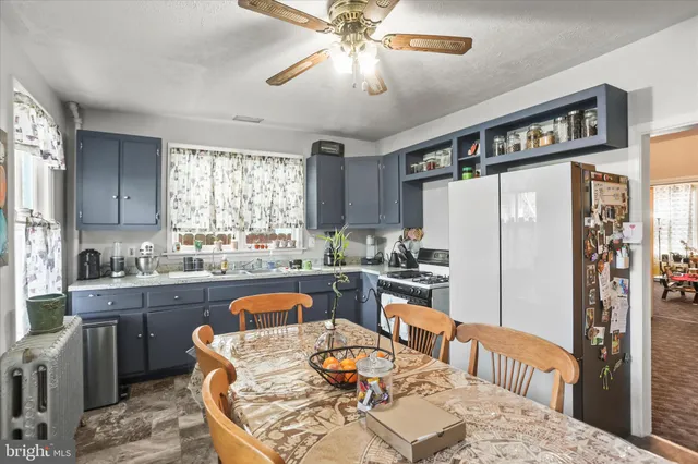 a kitchen with stainless steel appliances granite countertop a refrigerator a sink dishwasher a dining table and chairs with wooden floor