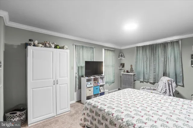 a bedroom with a bed and a flat tv screen on dresser