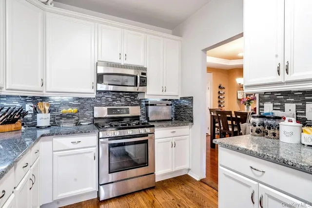 a kitchen with granite countertop a stove top oven a sink a counter space and cabinets