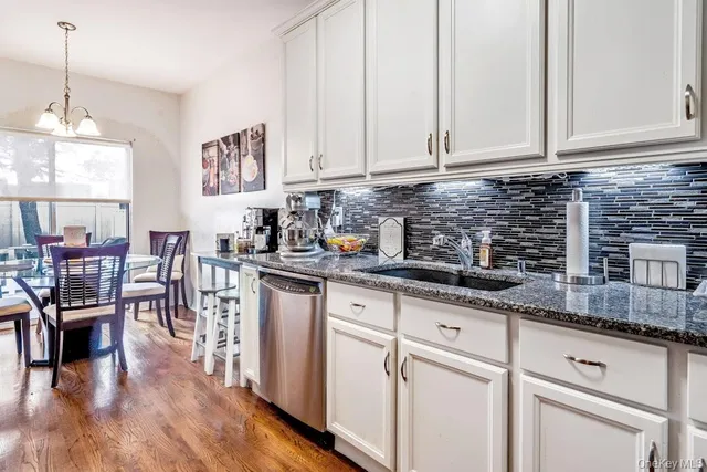 a kitchen with stainless steel appliances granite countertop a stove a refrigerator a sink a dining table and chairs with wooden floor