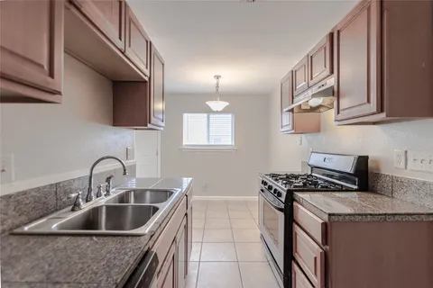 a kitchen with granite countertop a sink a stove and cabinets