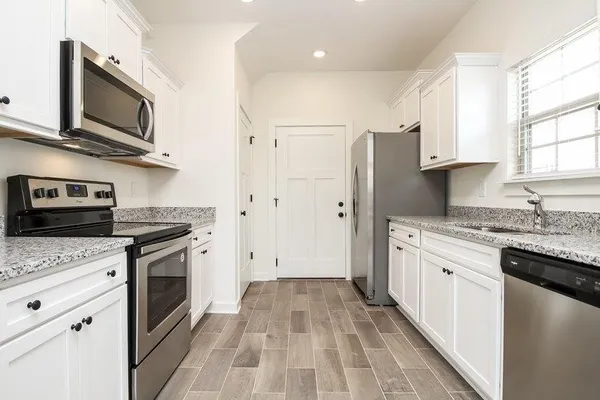 a kitchen with stainless steel appliances granite countertop hardwood floor sink stove and granite counter top